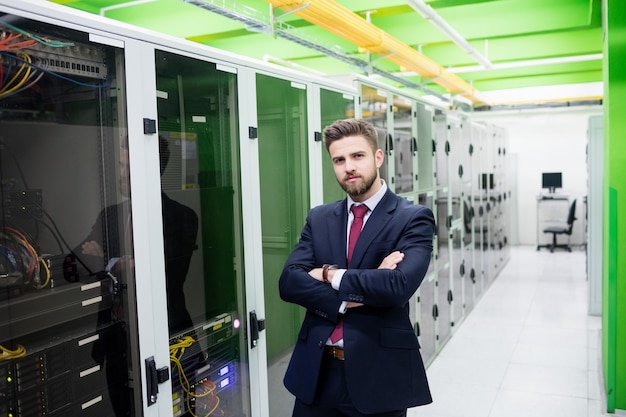 Technician standing with arms crossed in a server room