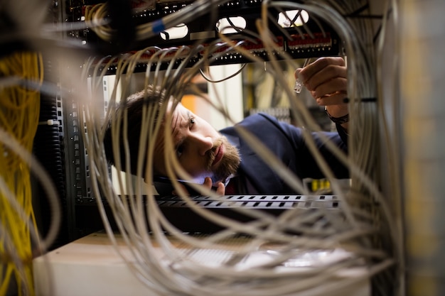 Technician talking on mobile phone while checking cables