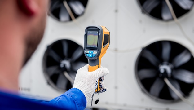 Technician uses a thermal imaging infrared thermometer to check the condensing unit heat exchanger