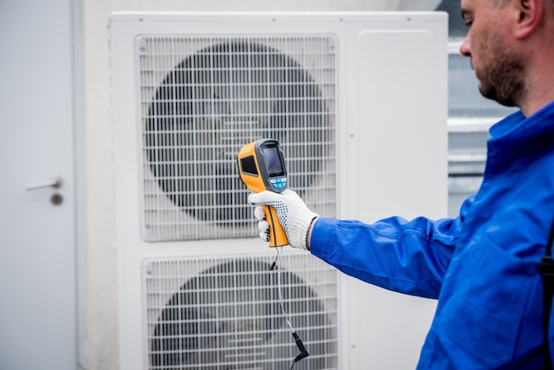 Technician uses a thermal imaging infrared thermometer to check the condensing unit heat exchanger