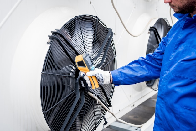 Technician uses a thermal imaging infrared thermometer to check the condensing unit heat exchanger