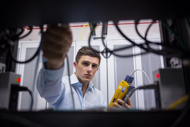 Technician using cable tester while fixing server