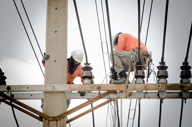 Technicians are repairing high voltage transmission systems on electric  poles