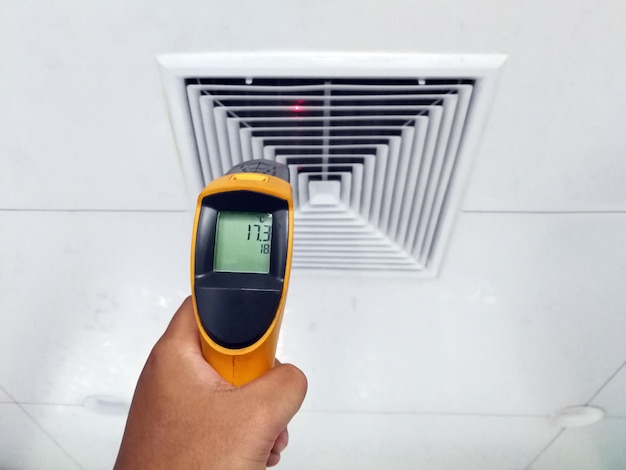 Technicians are using an infrared thermometer to check the temperature of the air supply surface