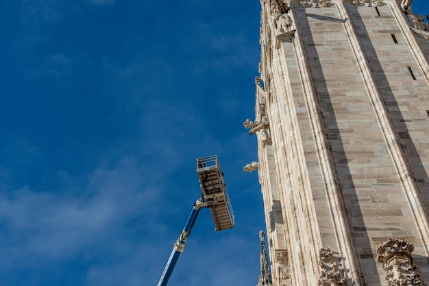 Technicians on lifting platform for scheduled maintenance plan and study of the degradation phenomena of the Milan cathedral