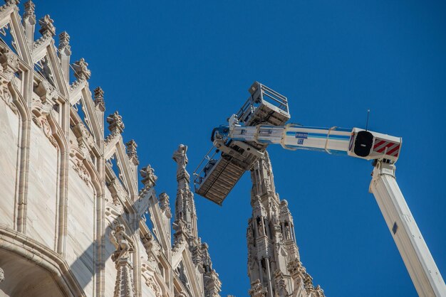 Technicians on lifting platform for scheduled maintenance plan\
and study of the degradation phenomena of the milan cathedral