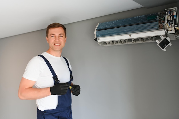 Technicus die airconditioner op de muur herstelt