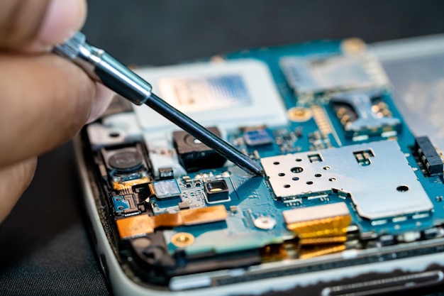 Technicus die de binnenkant van de mobiele telefoon repareert door soldeerbout Integrated Circuit het concept van data-hardwaretechnologie