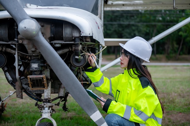 Technicus die de motor van het vliegtuig repareert Vrouwelijke lucht- en ruimtevaarttechniek die vliegtuigmotoren controleert Aziatisch monteuronderhoud inspecteert vliegtuigmotor