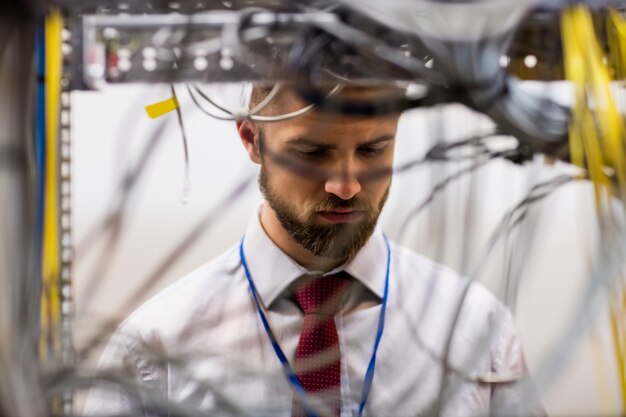 Foto technicus die kabels in een in een rek gemonteerde server controleert