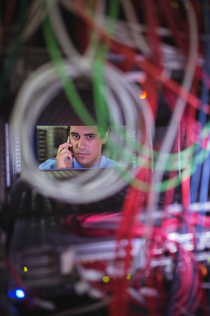 Foto technicus die op mobiele telefoon spreekt terwijl het controleren van kabels