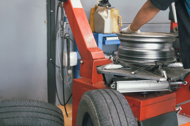 Technicus die rubber verwijdert uit autowielschijf & in evenwicht brengende band op balancer in autoreparatiegarage