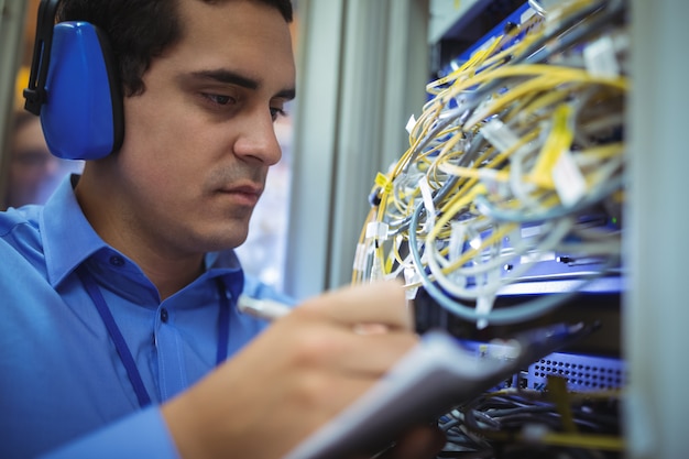 Technicus die verslag van in een rek gemonteerde server op klembord bijhoudt