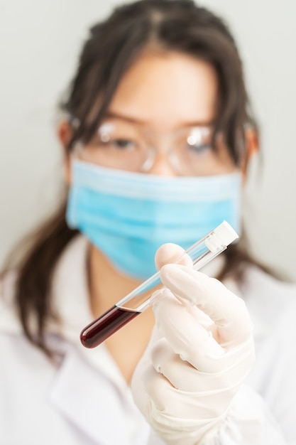 Technicus wetenschapper analyseren bedrijf bloedmonster in reageerbuis in laboratorium om te testen