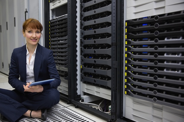 Foto technicus zittend op de vloer naast server toren met behulp van tablet pc