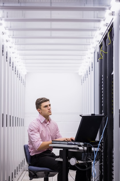 Foto technicuszitting op draaistoel die laptop met behulp van om servers te diagnostiseren