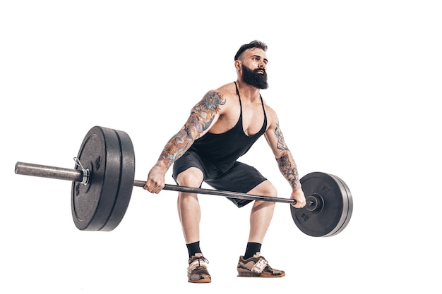 The technique of doing an exercise of deadlift with a barbell of a muscular strong tattooed bearded sports men 