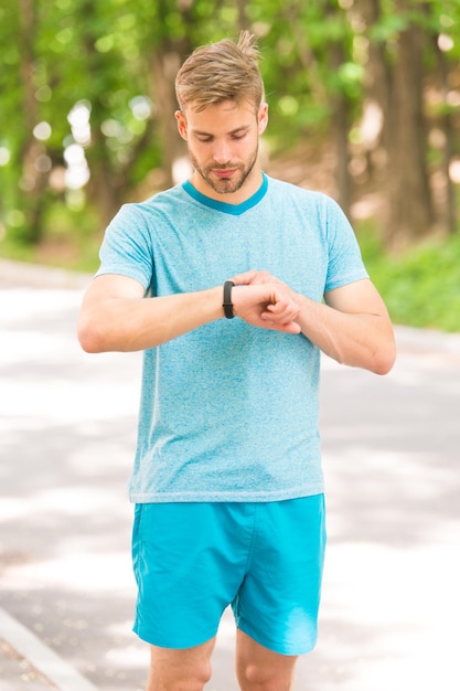 Technologie combineren met stijl Fit man volgt zijn prestaties met sporthorloge-technologie Knappe atleet die smartwatch-technologie gebruikt tijdens training Technologie maakt sporttraining slimmer