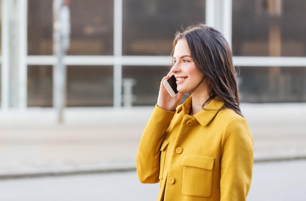 technologie, communicatie en mensenconcept - glimlachende jonge vrouw of meisje die smartphone op stadsstraat roepen