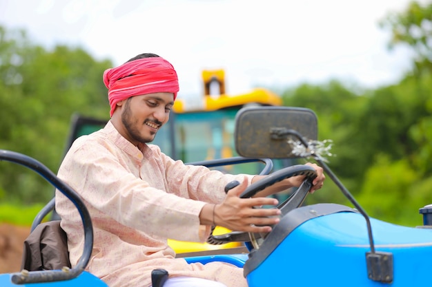 Technologie en mensen concept, portret van jonge Indiase boer met tractor