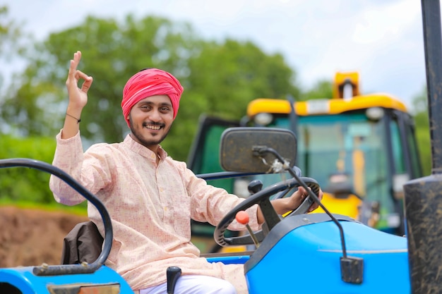 Technologie en mensen concept, portret van jonge Indiase boer met tractor