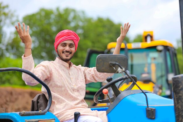 Technologie en mensen concept, portret van jonge Indiase boer met tractor