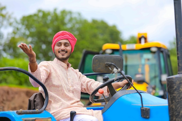 Technologie en mensen concept, portret van jonge indiase boer met tractor