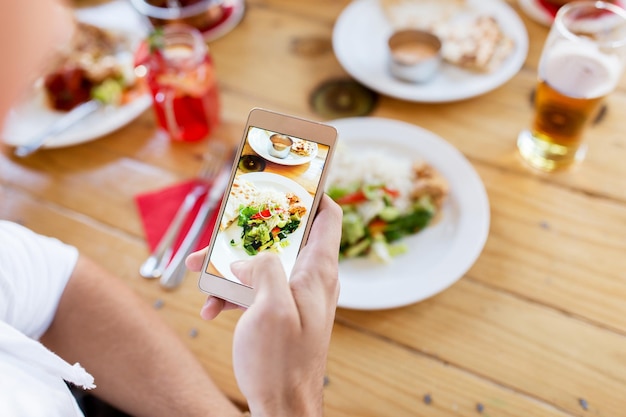 technologie, eten en mensenconcept - hand met smartphone fotograferen van eten in restaurant