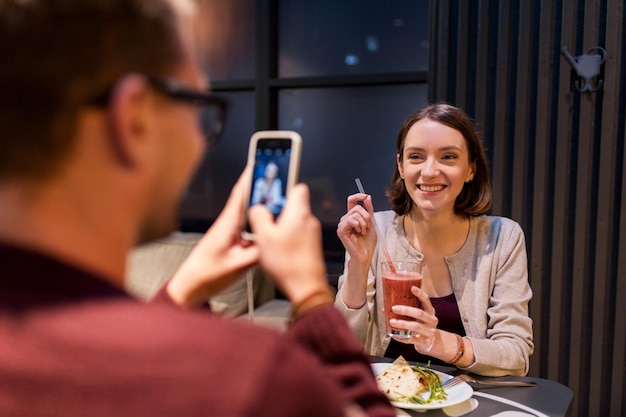technologie, eten, vegetarisch eten en mensenconcept - gelukkige man met smartphone fotograferen in veganistisch restaurant