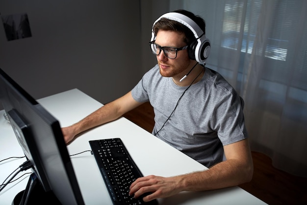 technologie, gaming, entertainment, laten we spelen en mensenconcept - jonge man in headset en bril met pc-computer die thuis een game speelt en playthrough of walkthrough-video streamt