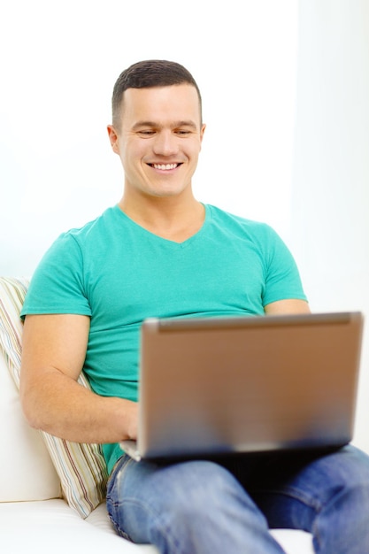 technologie, huis en levensstijlconcept - glimlachende mens die met laptop thuis werkt
