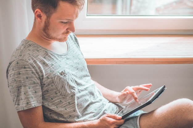 Technologie, huis - levensstijl concept close-up van man aan het werk met de tabletcomputer en zittend op een stoel thuis