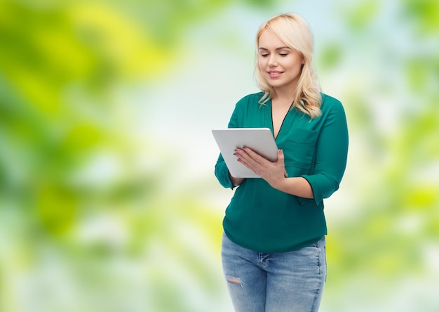 technologie, internet en mensen concept concept - lachende vrouw met tablet pc-computer over groene natuurlijke achtergrond