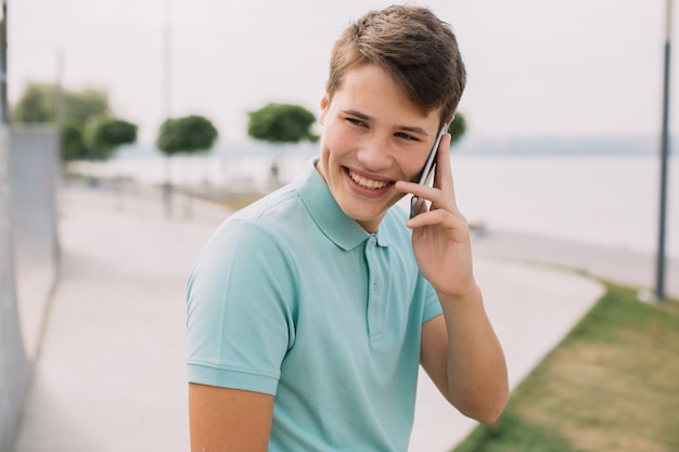 Technologie, internet en mensenconcept - gelukkige tiener met smartphone in openlucht.