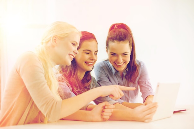 Foto technologie, internet, school en onderwijsconcept - groep glimlachende tienerstudenten met tablet-pc-computer op school