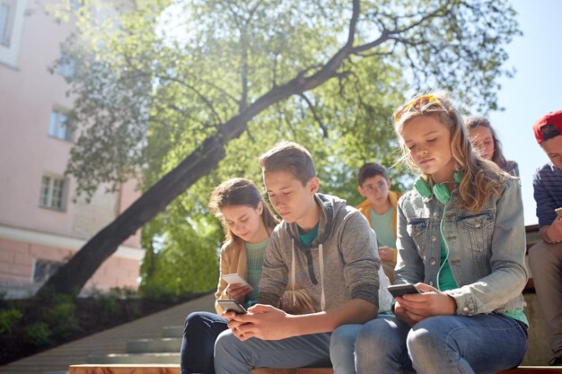 technologie, internetverslaving en mensenconcept - groep tienervrienden of middelbare scholieren met smartphones buitenshuis