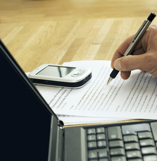 Technologie is essentieel geworden voor het bestuderen van laptop en mobiel op tafel met iemand die aantekeningen maakt