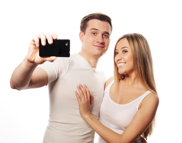 Technologie liefde en vriendschap concept glimlachend paar met smartphone selfie en plezier Studio opnames op witte achtergrond