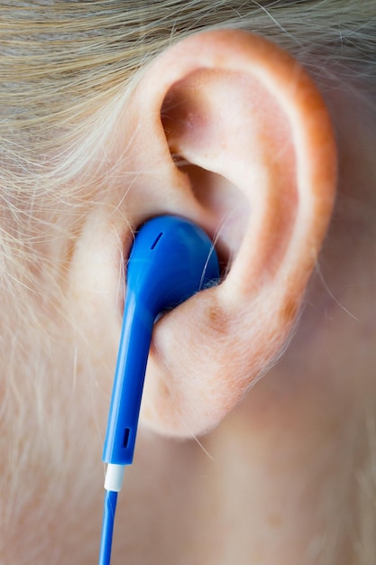 technologie, muziek en mensenconcept - close-up van vrouw in oortelefoons thuis