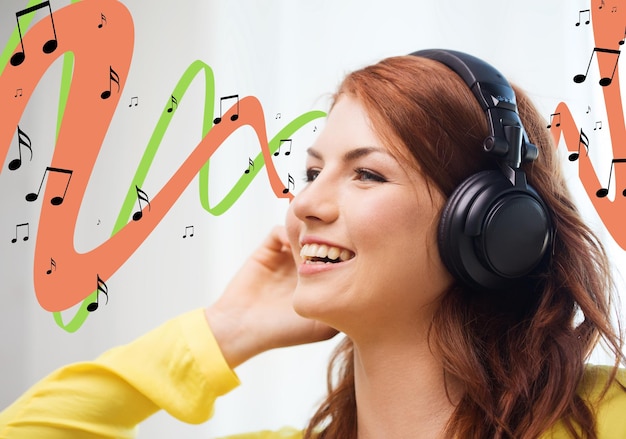 technologie, muziek, mensen en geluk concept - glimlachend tienermeisje in koptelefoon thuis