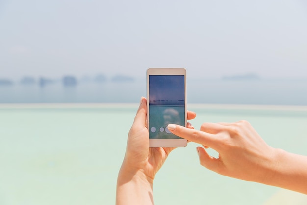 technologie, reizen, toerisme, communicatie en mensen concept - close-up van mannelijke hand met smartphone op zomerstrand