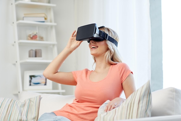 technologie, virtual reality, cyberspace, entertainment en mensenconcept - gelukkige jonge vrouw met virtual reality-headset of 3D-bril zittend op de bank thuis