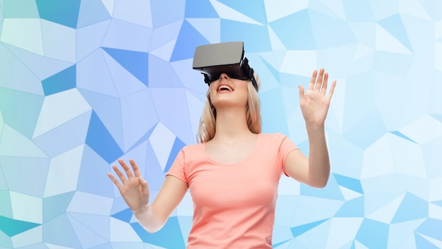 technologie, virtual reality, entertainment en mensenconcept - gelukkige jonge vrouw met virtual reality-headset of 3D-bril blauwe laag poly textuur achtergrond