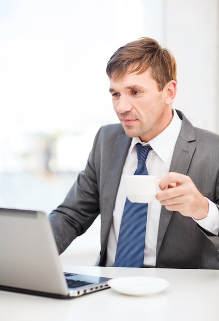 technologie, zaken en bureauconcept - knappe zakenman die met laptop computer werkt