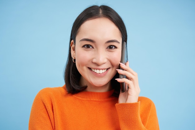 Technologieconcept close-up van lachende Aziatische vrouw praat op mobiele telefoon met gesprek op cel