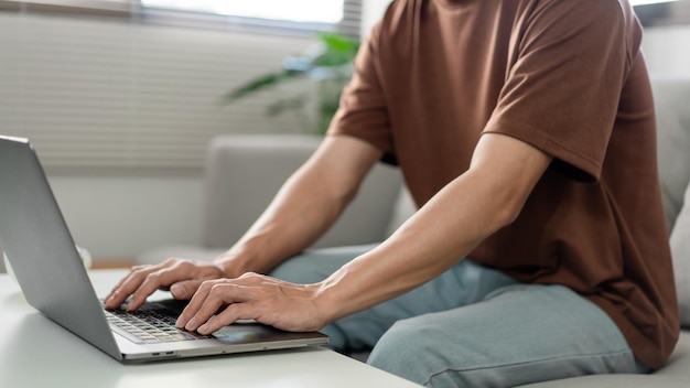 Technologieconcept De man in het bruine T-shirt die zich concentreert op het typen van iets op zijn computerlaptop