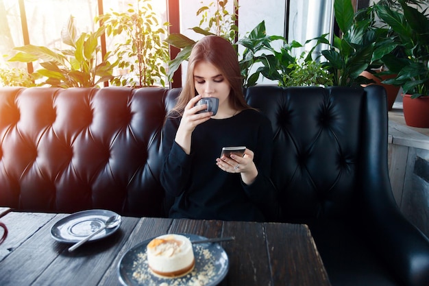 Technologieën emoties levensstijl mensen tieners concept jonge gelukkige vrouwelijke lezen op haar mobiele telefoon zittend in moderne coffeeshop interieur prachtige hipster meisje met mooie glimlach