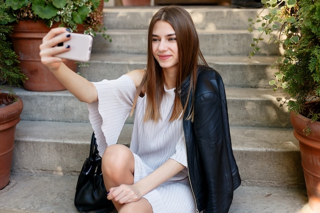 Technologieën, emoties, mensen, schoonheid, mode en levensstijlconcept - jonge schoonheidsvrouw maakt selfie voor zelfsmartphone, openluchtportret, fotomodel, mooi meisje, hipster, schoonheidsstraatfoto