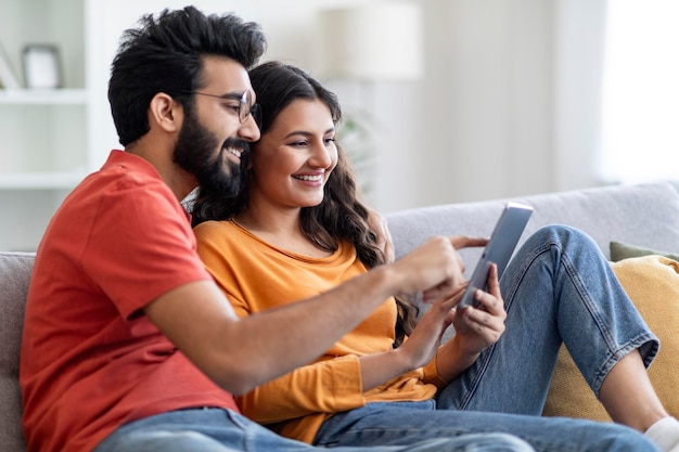 Technologieën voor ontspanning gelukkige Indiase echtgenoten die thuis een digitale tablet gebruiken