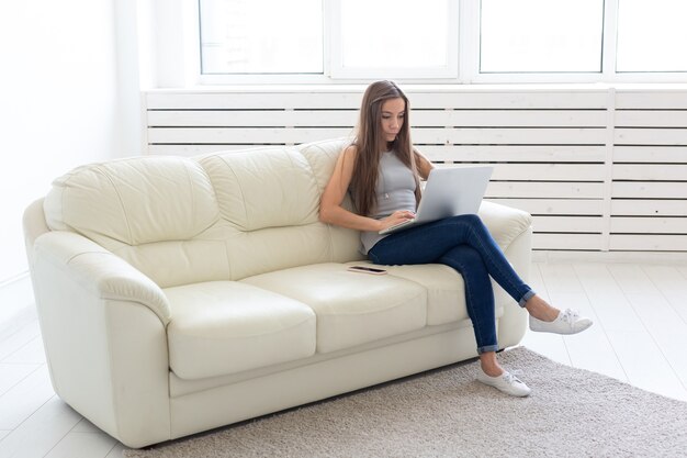 Photo technologies, freelance and people concept. young woman sitting on the white sofa and chatting with laptop